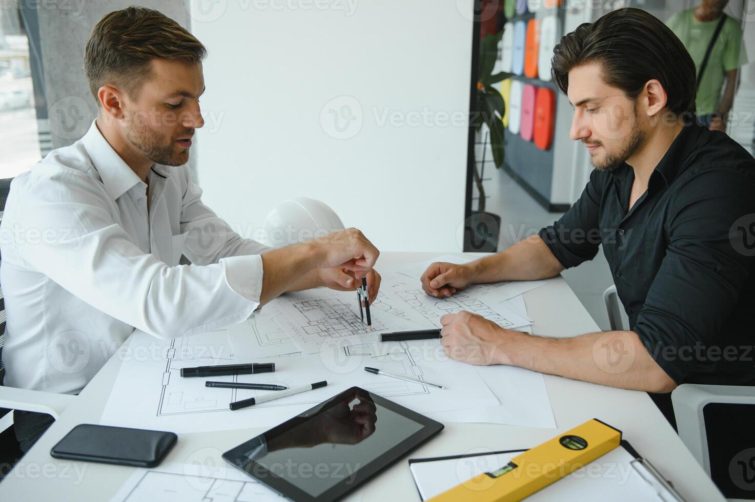 two people sit in front of construction plan and talk about the architecture photo