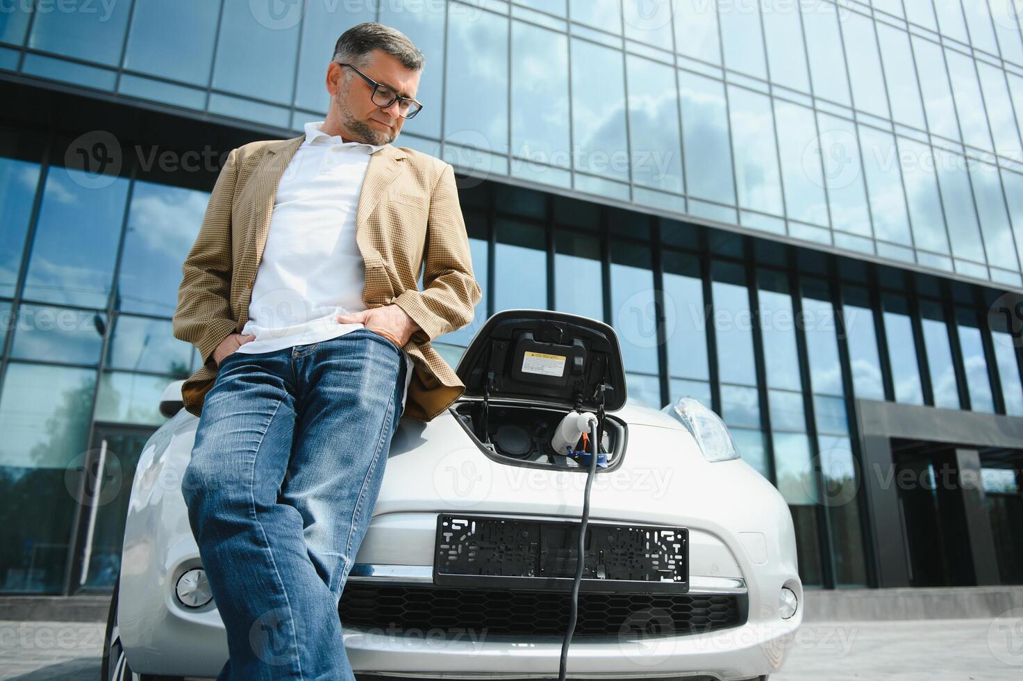 Man charges an electric car at the charging station photo