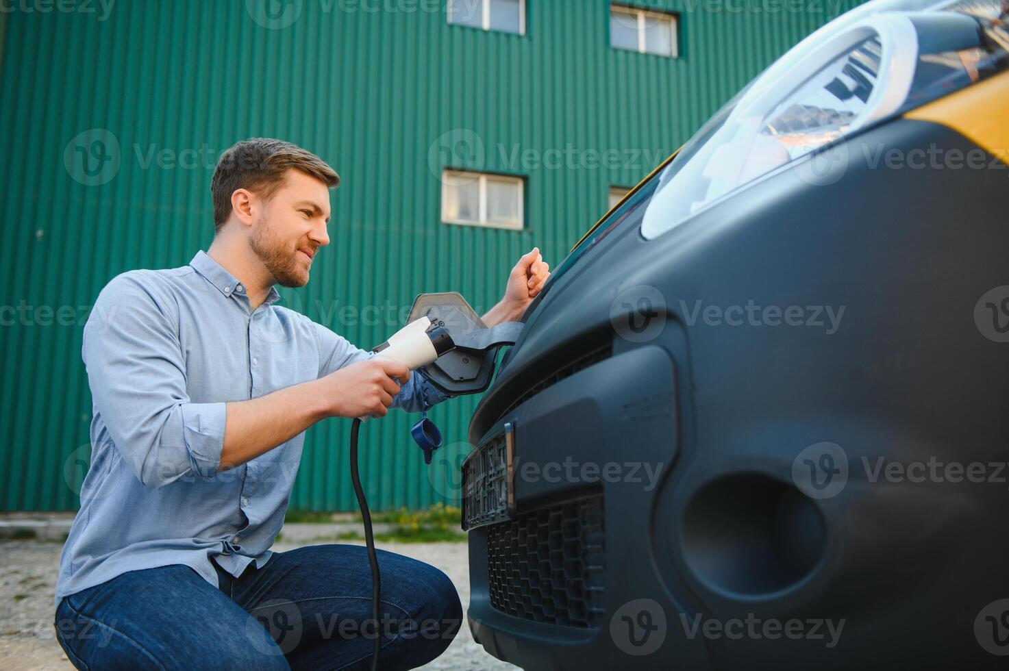 Smiling man unplugging the charger from the car photo