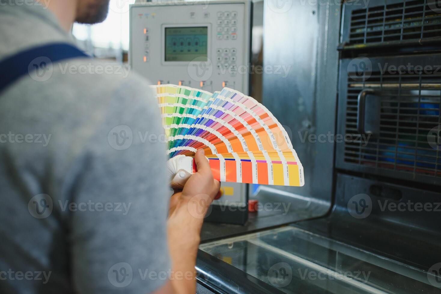 Man working in printing house with paper and paints photo