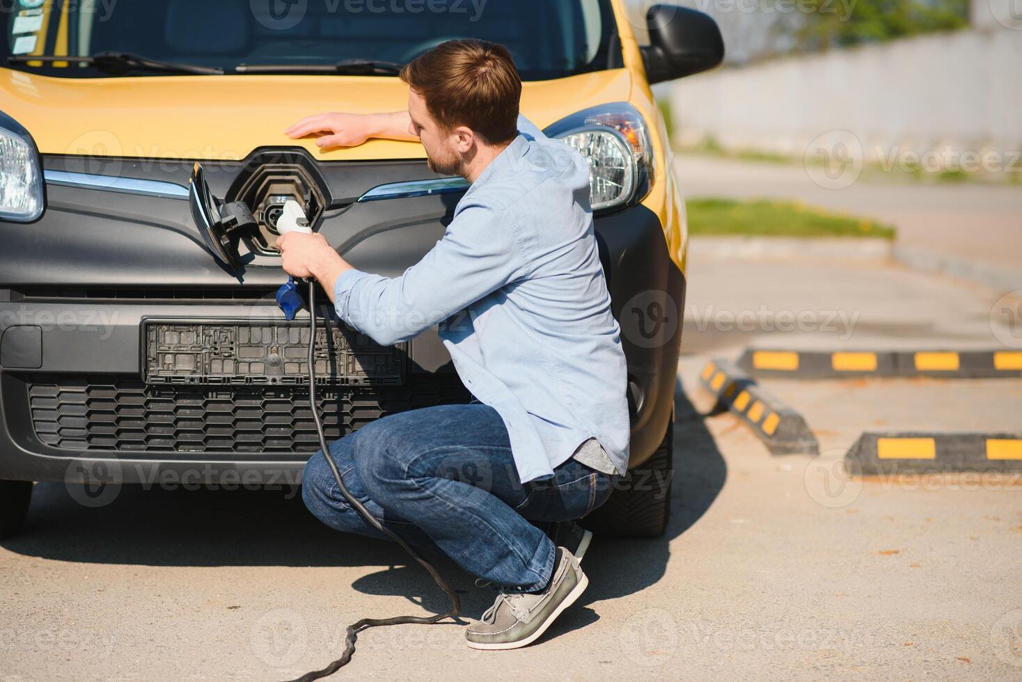 Smiling man unplugging the charger from the car photo