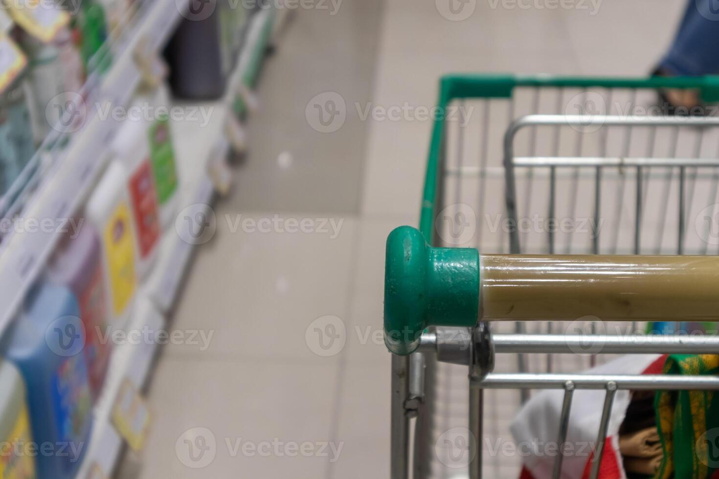 Empty green shopping cart in supermarket aisle photo