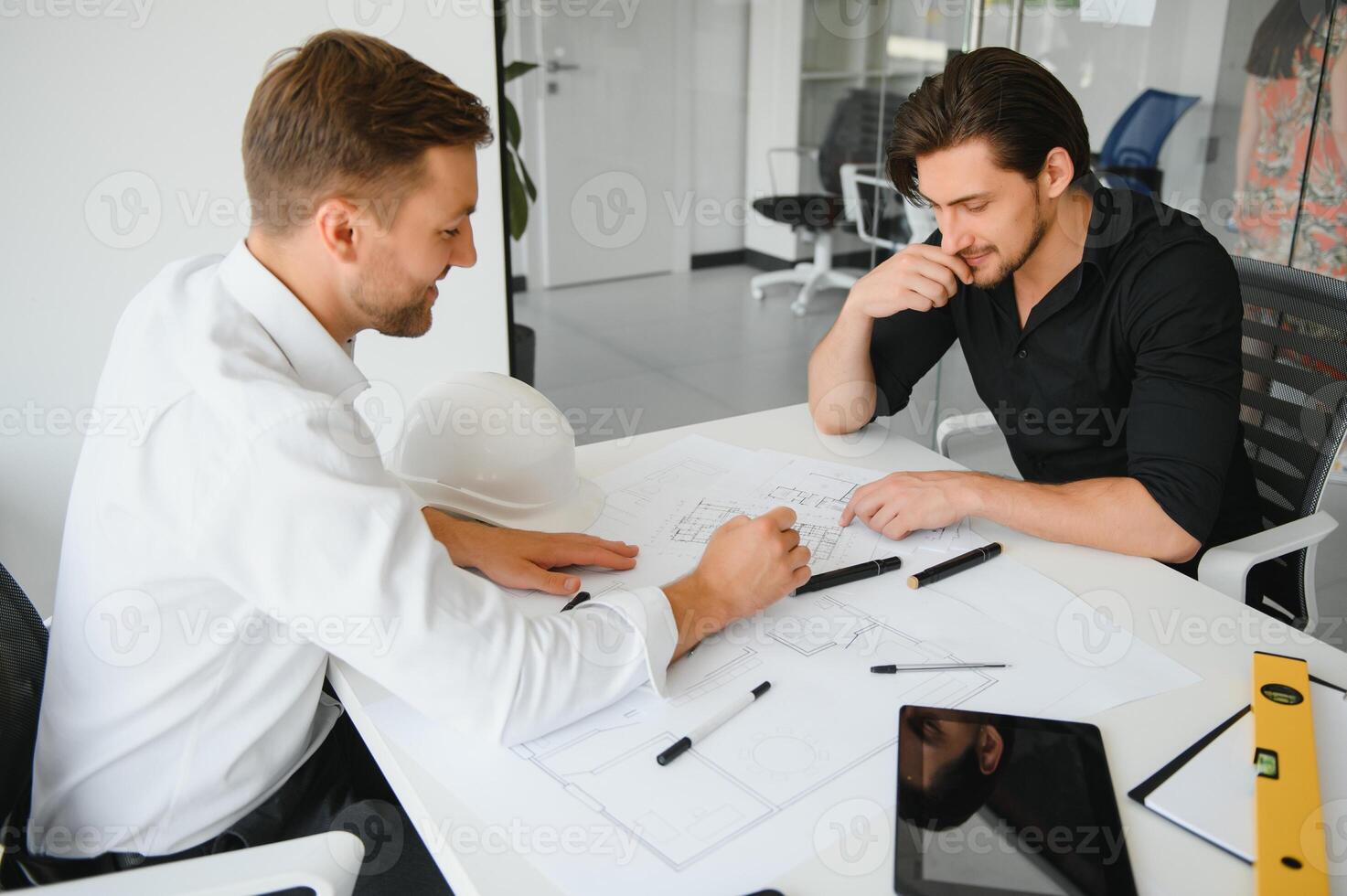 two people sit in front of construction plan and talk about the architecture photo