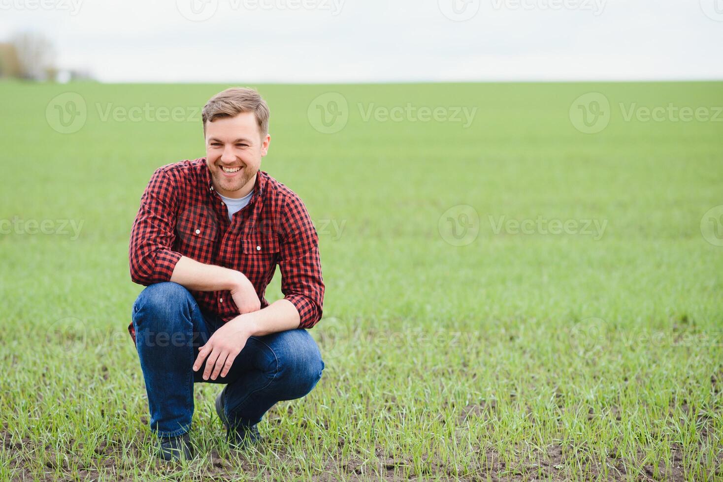 Handsome farmer. Young man walking in green field. Spring agriculture. photo