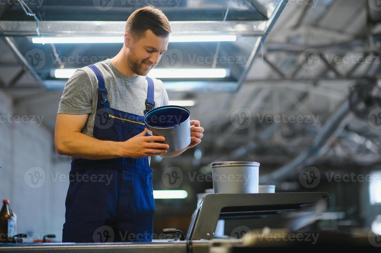 Man working in printing house with paper and paints photo
