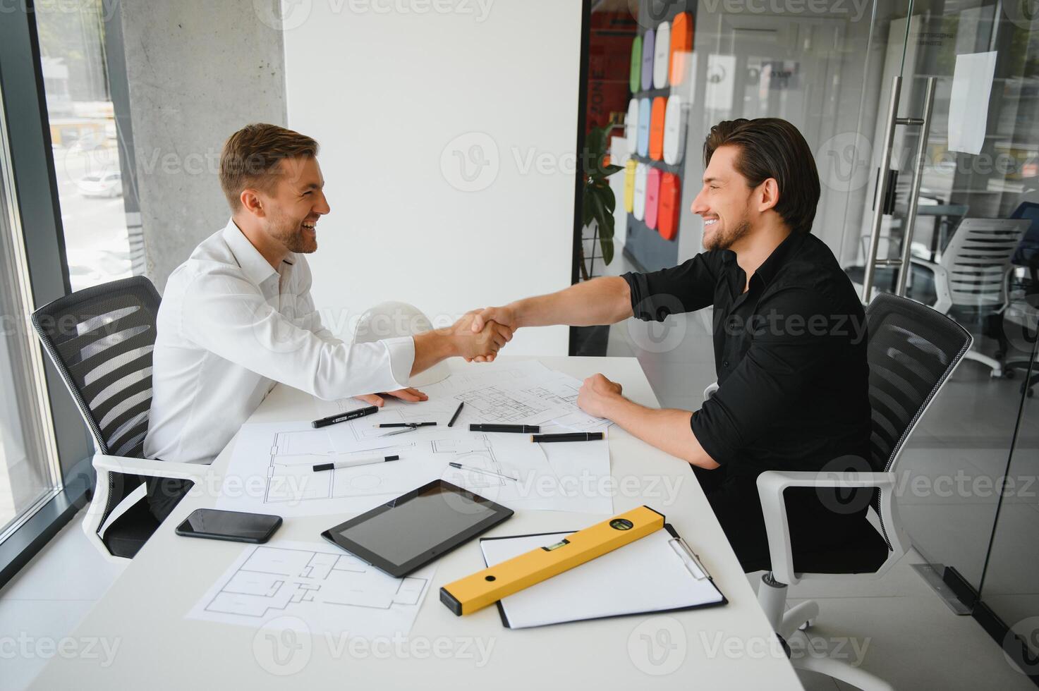 Two engineering working together and using digital tablet looking blueprint and analysis with architectural plan on desk photo