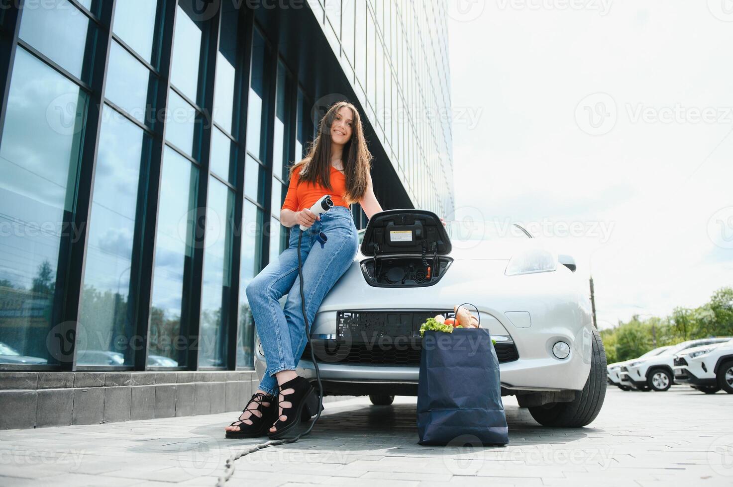 mujer cargando electro coche a el eléctrico gas estación foto