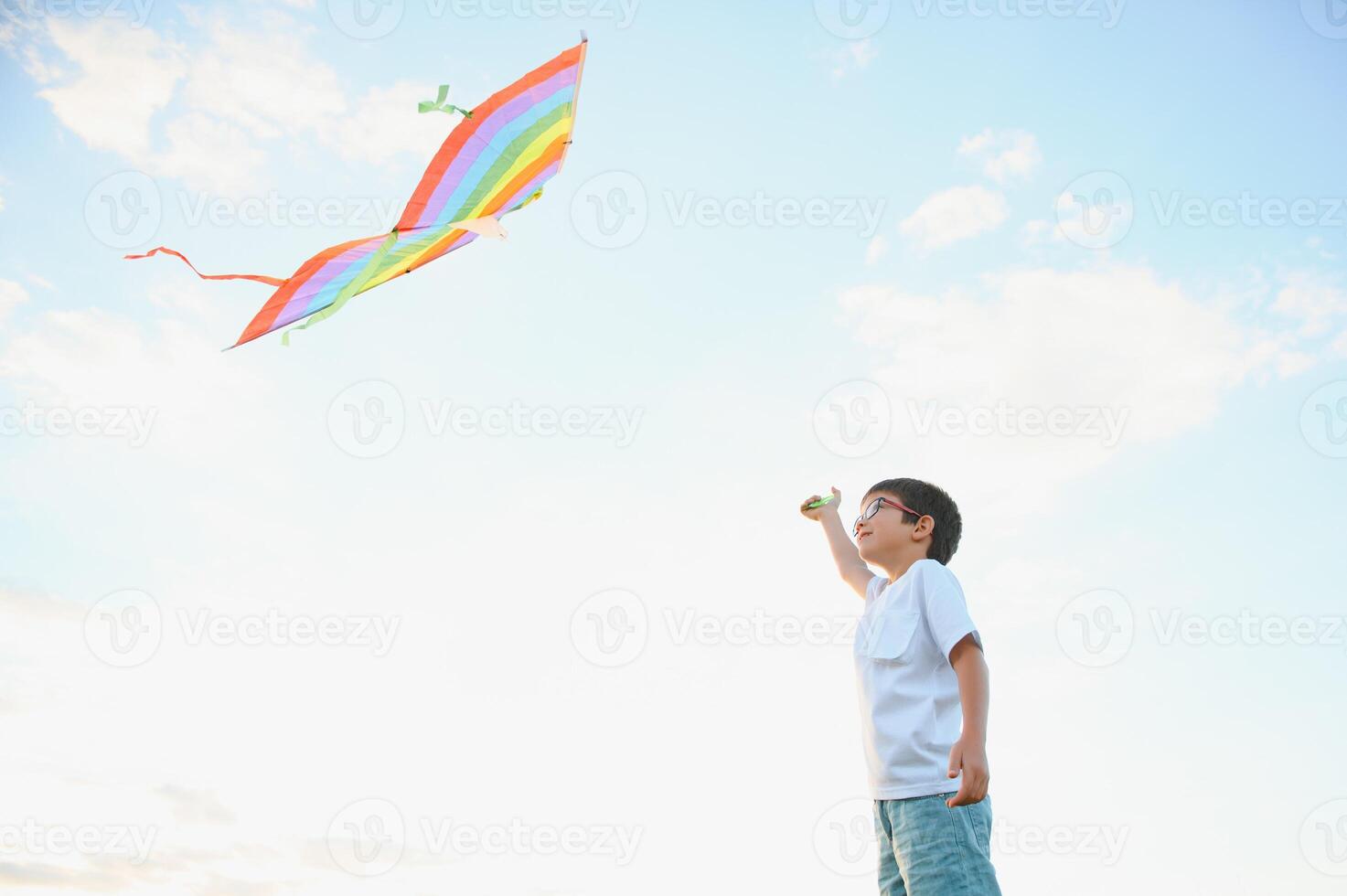 Boy is running with a kite during the day in the field photo