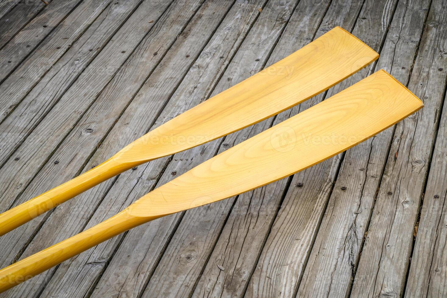 blades of wooden rowing oars against rustic, grunge wood deck photo