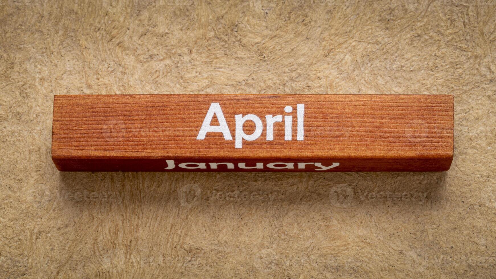 April and January text on wooden block against handmade bark paper in earth tones, calendar concept photo