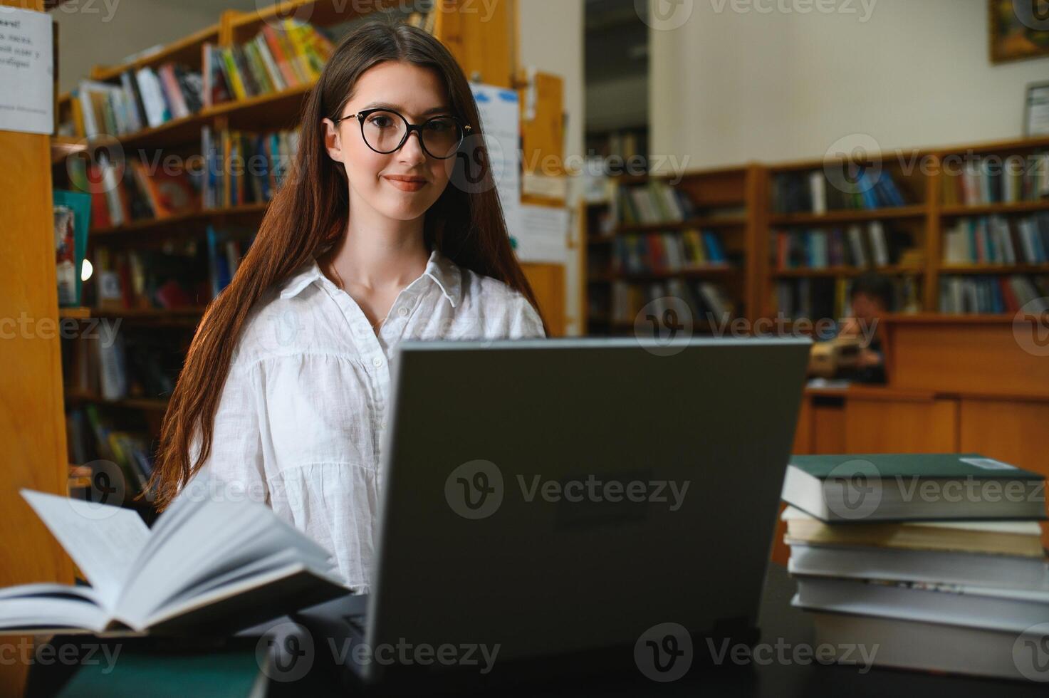 University Library Beautiful Smart Caucasian Girl uses Laptop, Writes Notes for Paper, Essay, Study for Class Assignment. Focused Students Learning, Studying for College Exams. Side View Portrait photo