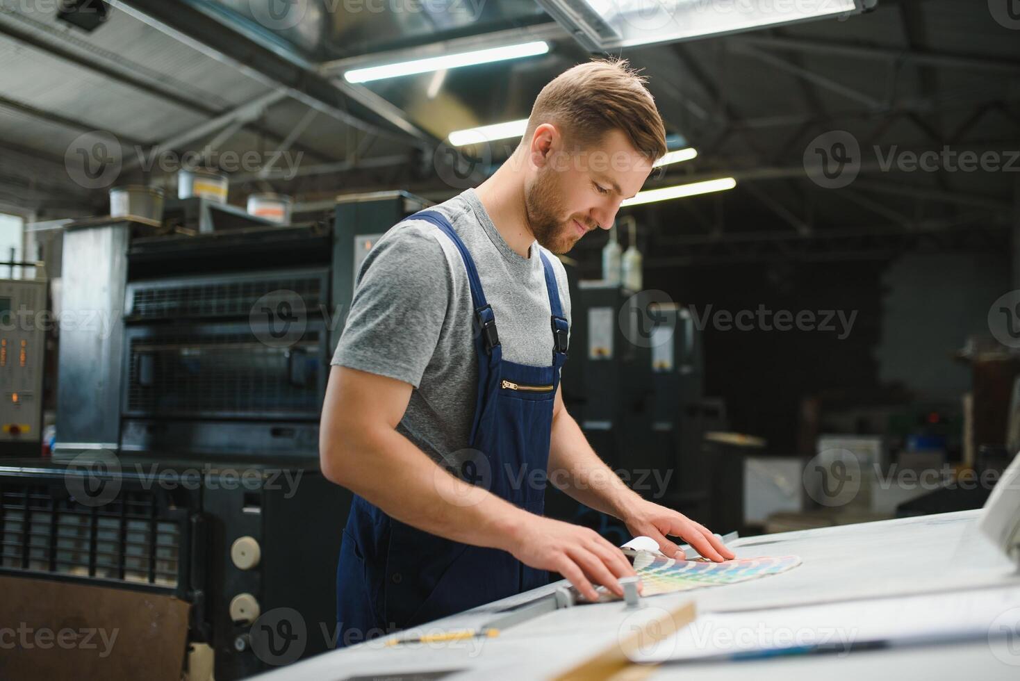 Man working in printing house with paper and paints photo