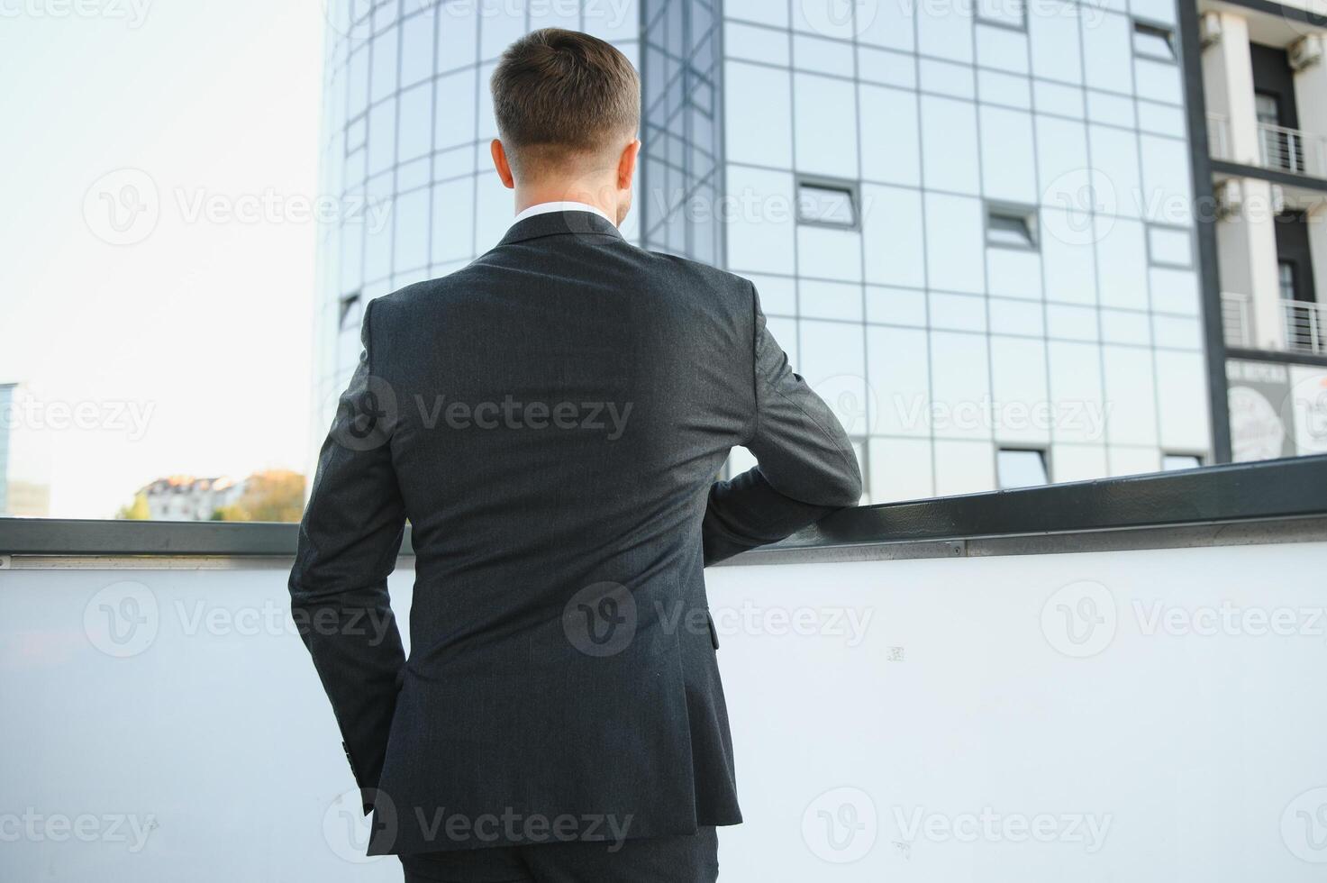 Modern businessman. Confident young man in full suit and looking away while standing outdoors with cityscape in the background photo