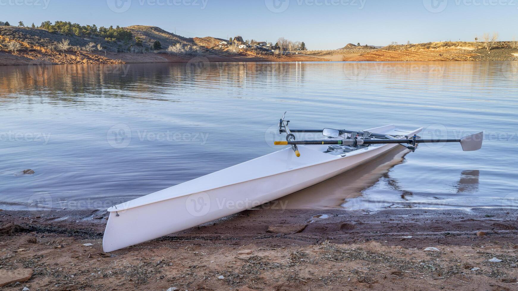 Coastal rowing shell on a shore of Horsetooth Reservoir in fall or winter scenery with a low water level. photo