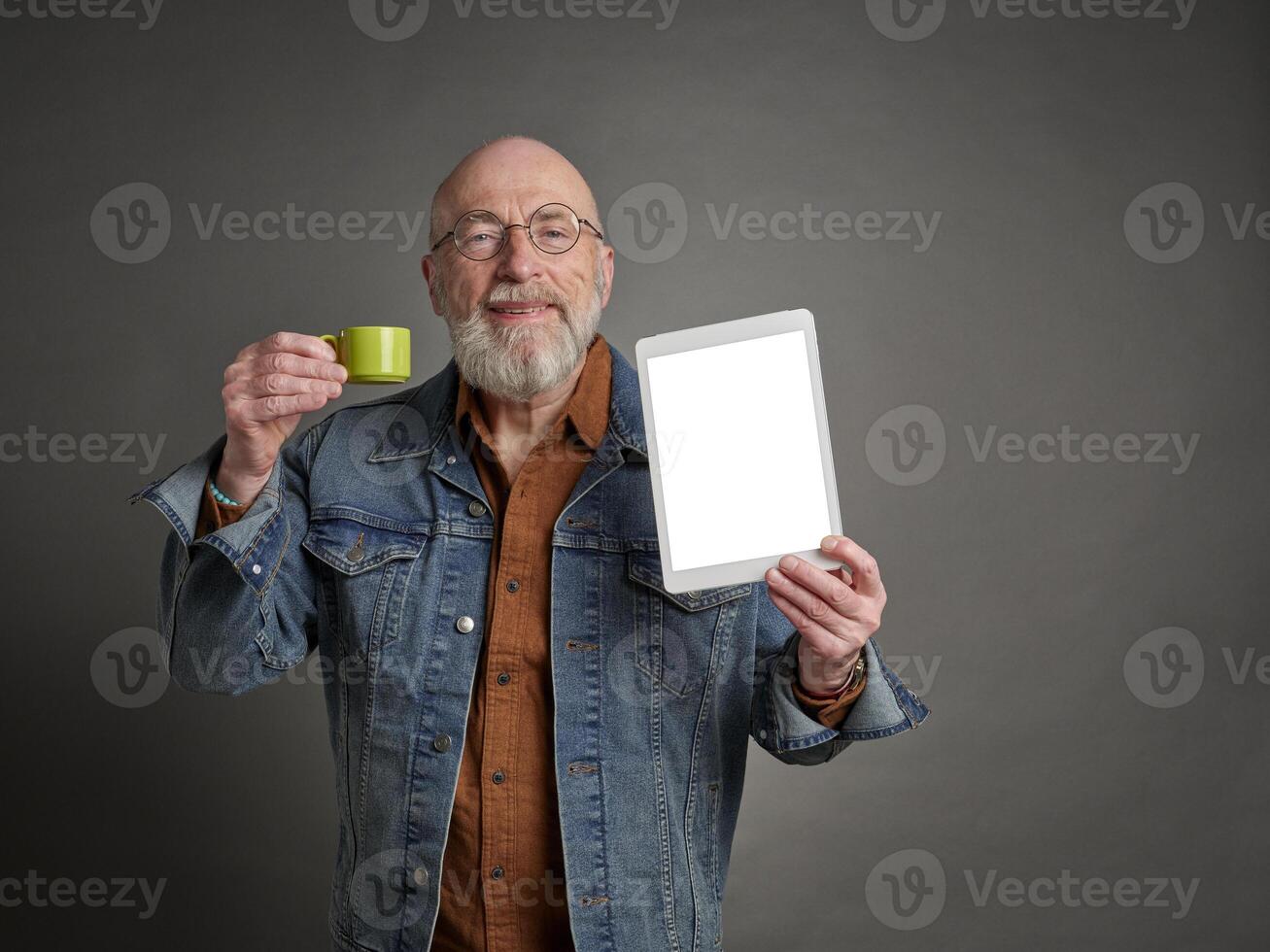 sonriente mayor hombre con un blanco digital tableta y un taza de café, enseñando y presentación concepto foto