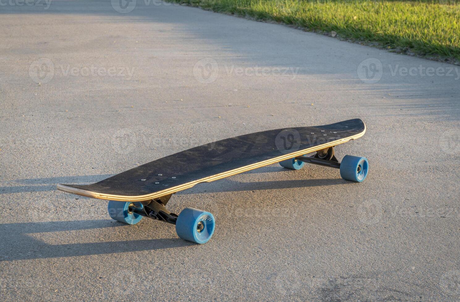 cruising longboard with blue wheels on a paved bike trail in summer scenery in northern Colorado photo