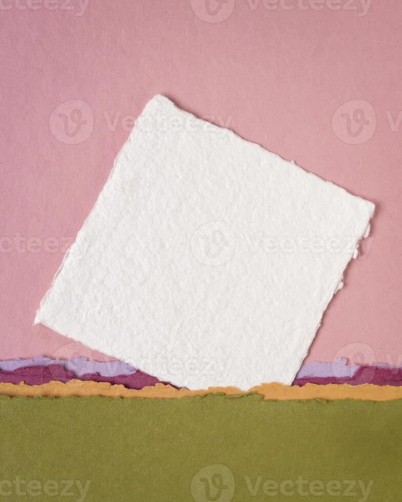 small sheet of blank white Khadi rag paper from India against abstract landscape in pink and green pastel tones photo
