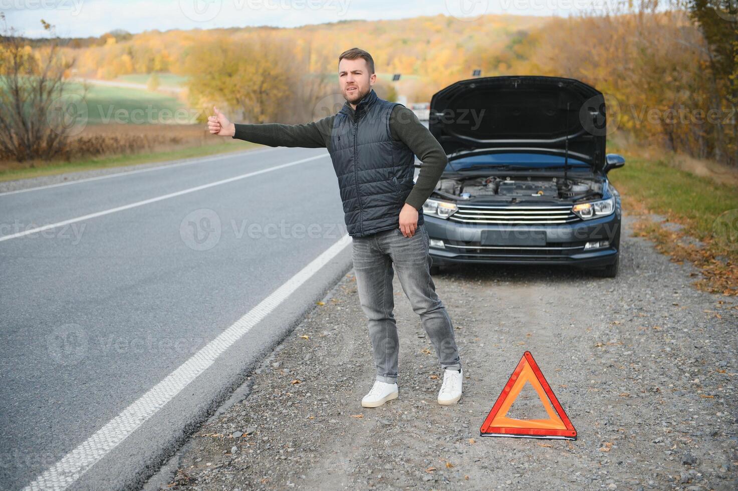 Man with broken car in the middle of the road. photo