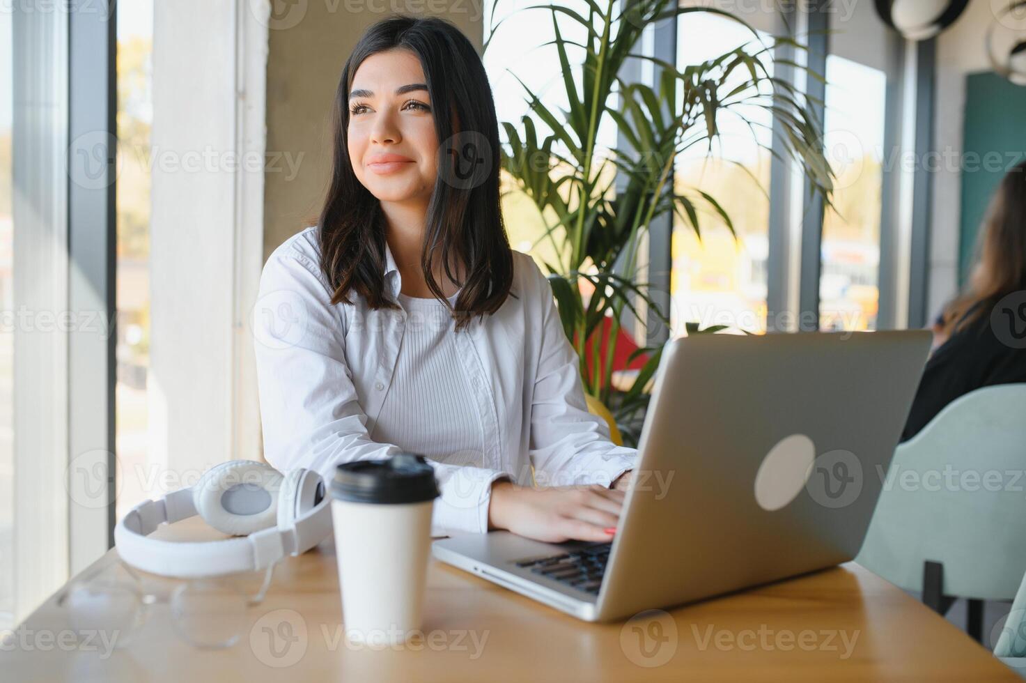 Beautiful Caucasian woman dreaming about something while sitting with portable net-book in modern cafe bar, young charming female freelancer thinking about new ideas during work on laptop computer photo