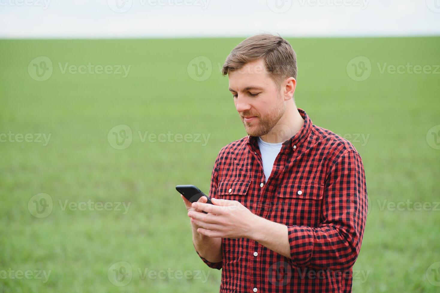 Handsome farmer. Young man walking in green field. Spring agriculture. photo