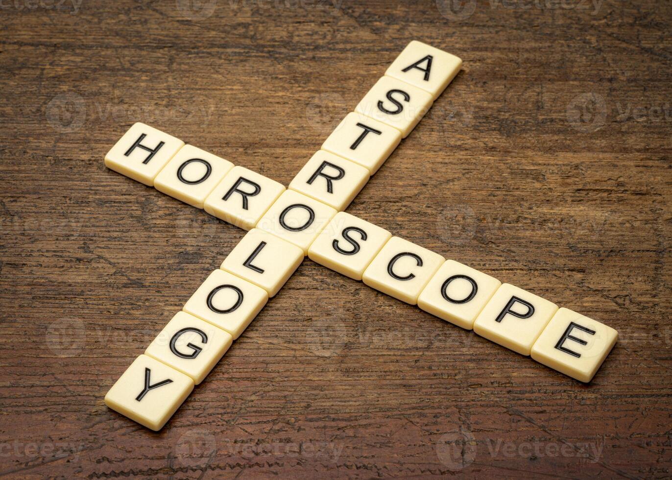 astrology and horoscope crossword in ivory letter tiles against rustic weathered wood photo