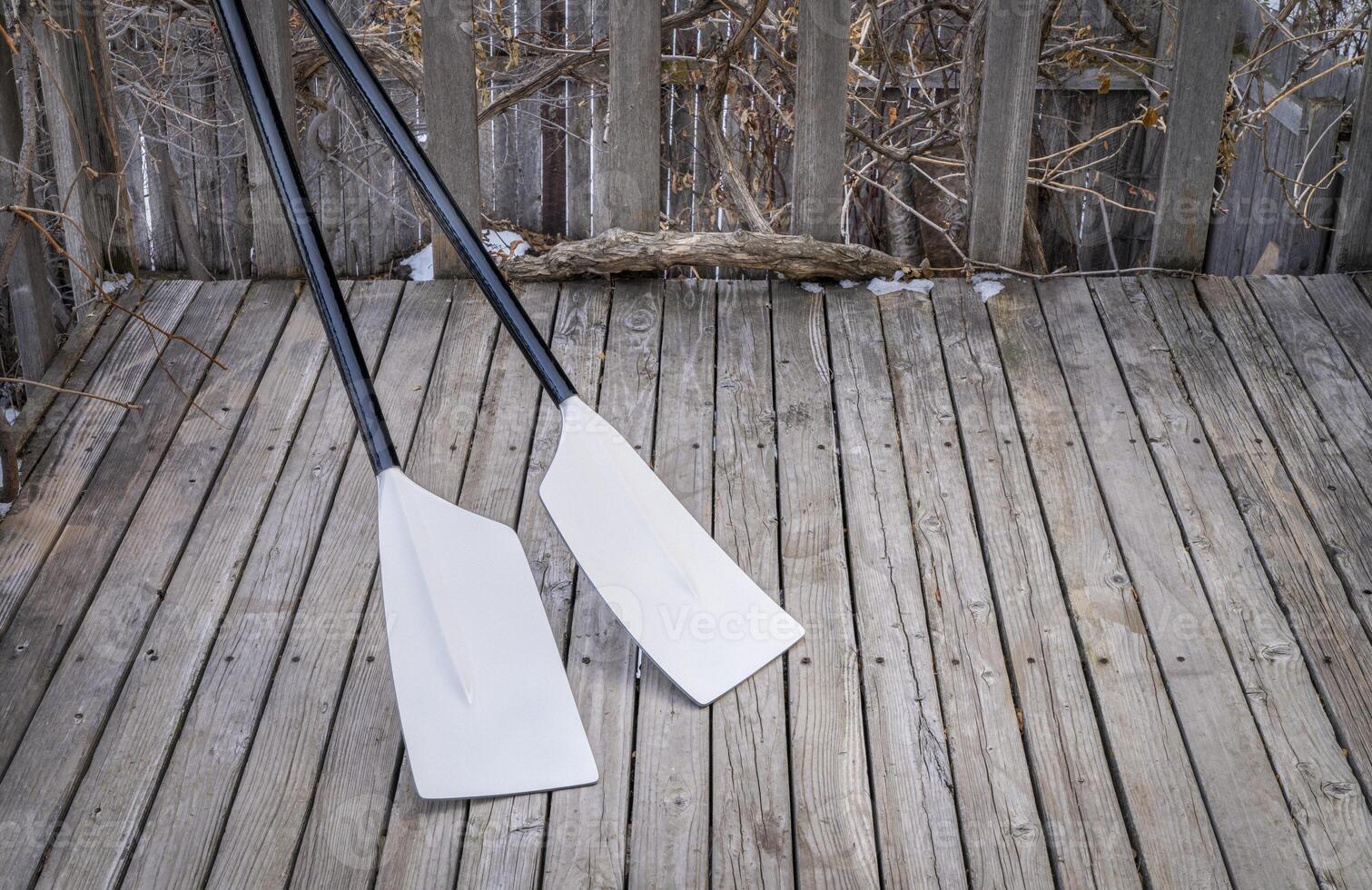 blades of hatchet sculling oars against grunge, rustic wooden deck photo