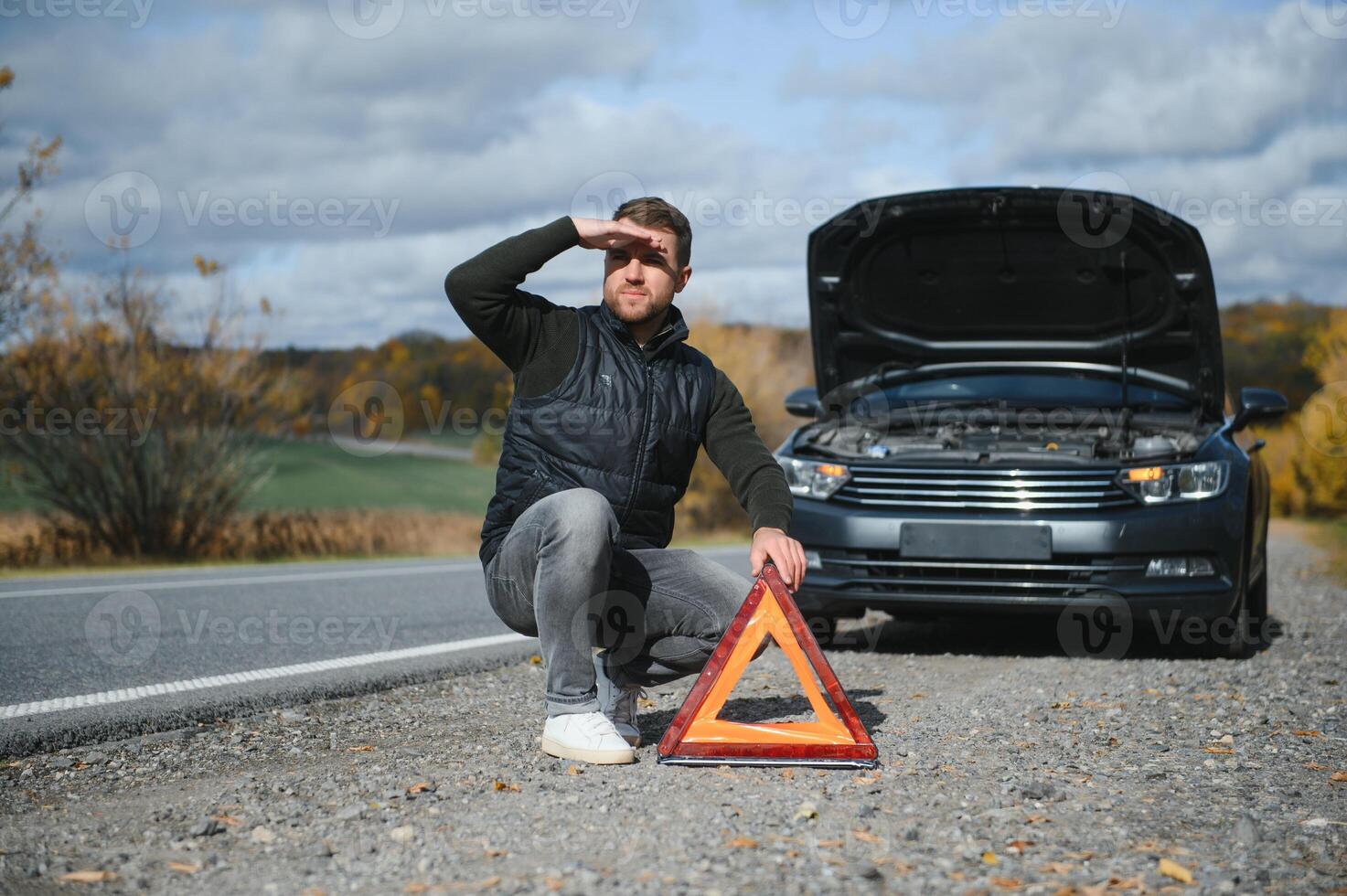 Handsome young man with his car broken down by the roadside photo