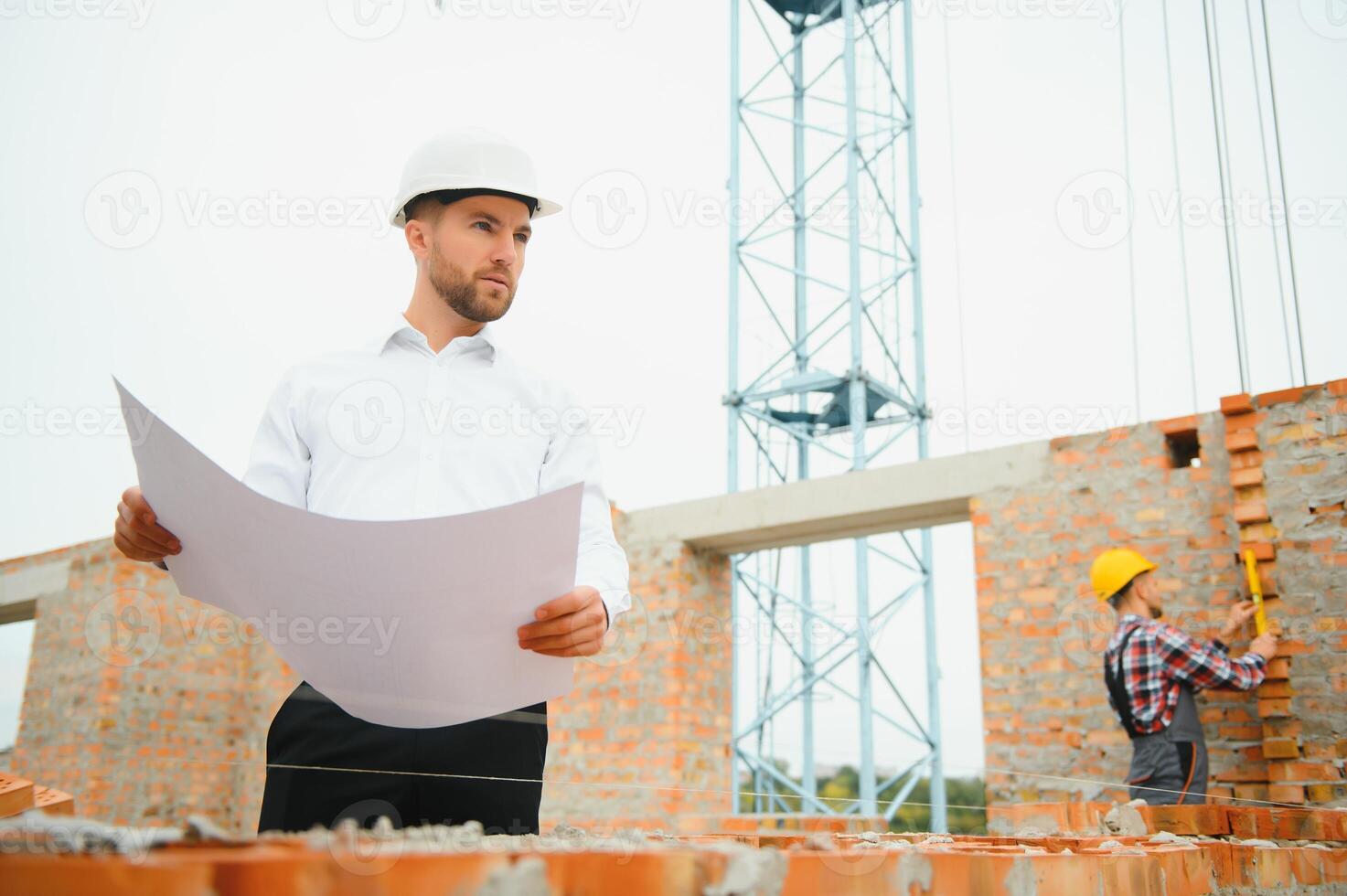 Construction engineer supervising progress of construction project stand on new concrete floor top roof and crane background. photo