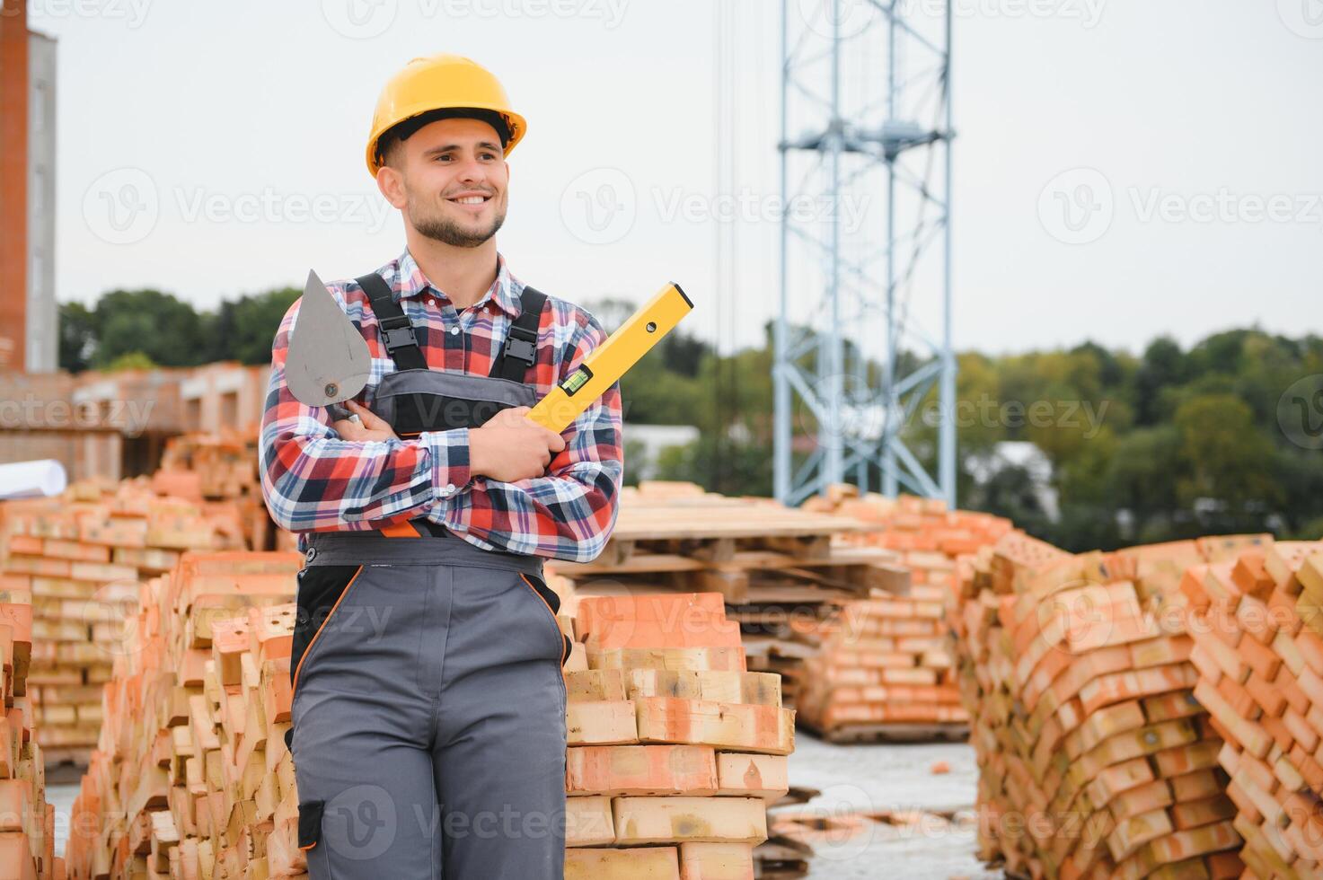 Using bricks. Young construction worker in uniform is busy at the unfinished building photo