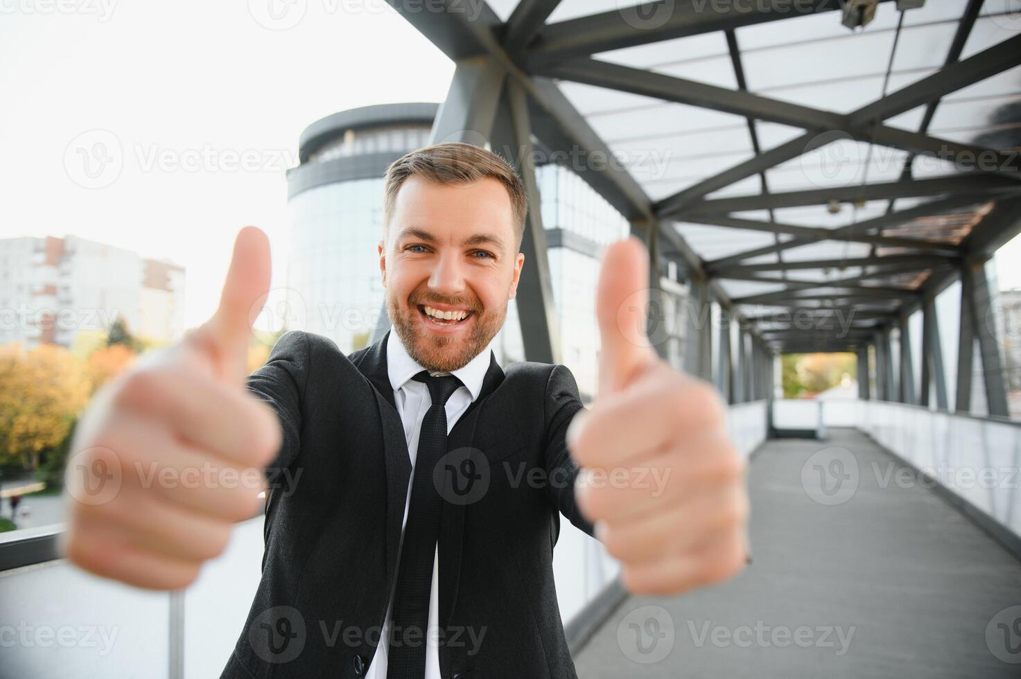 Successful businessman celebrating his victory with arms up on cityscape background. photo