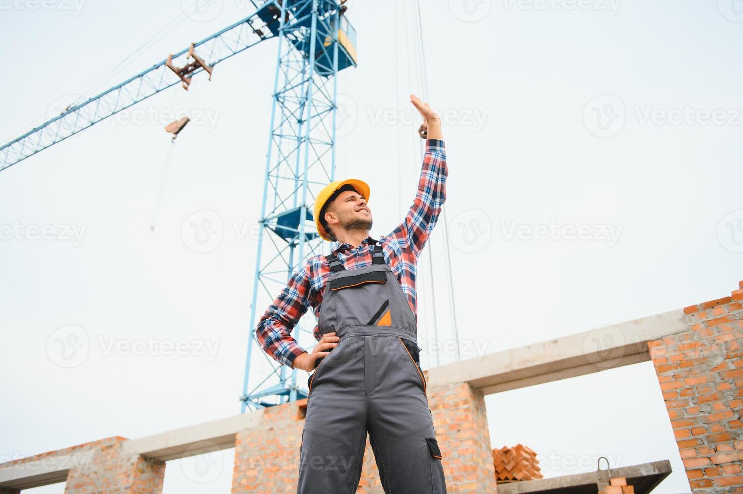 Communicating with crane guy. Construction worker in uniform and safety equipment have job on building. photo