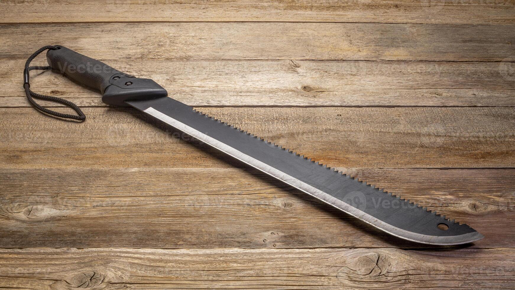 bush clearing machete with carbon steel blade and saw against rustic wooden deck photo