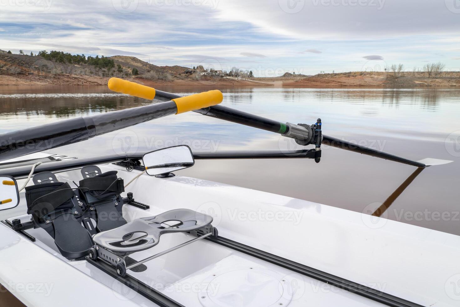 Detail of a coastal rowing shell with sculling oars, footstretcher, sliding seat and mirrors on a shore of Horsetooth Reservoir in northern Colorado photo