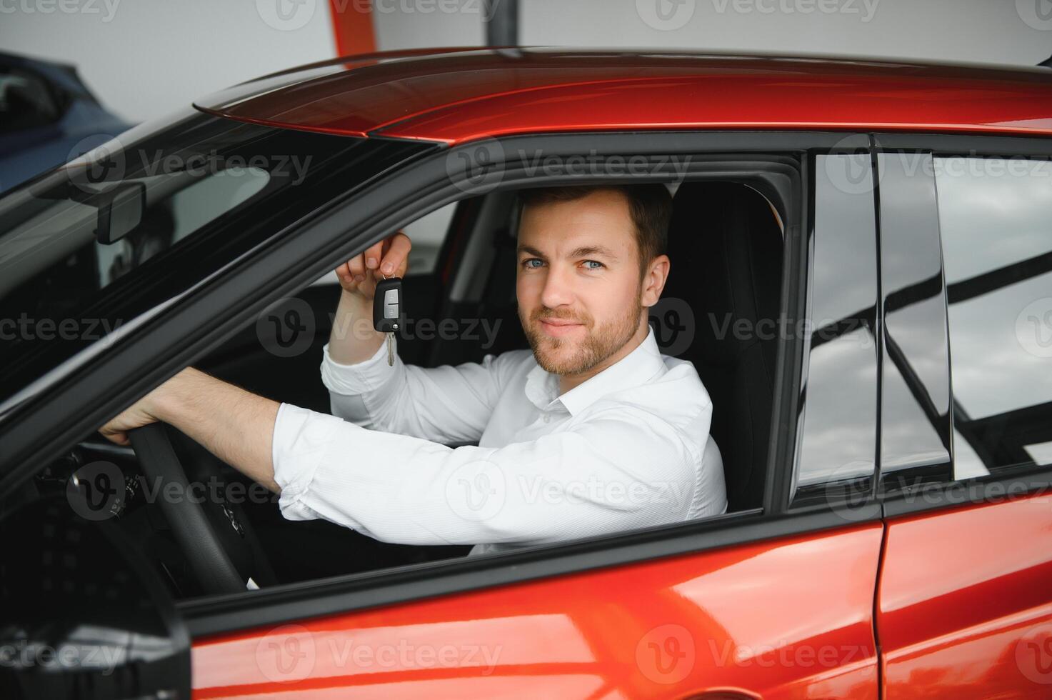 Yes, that's my new car. Customer in car dealership. Young man with keys in hand. photo