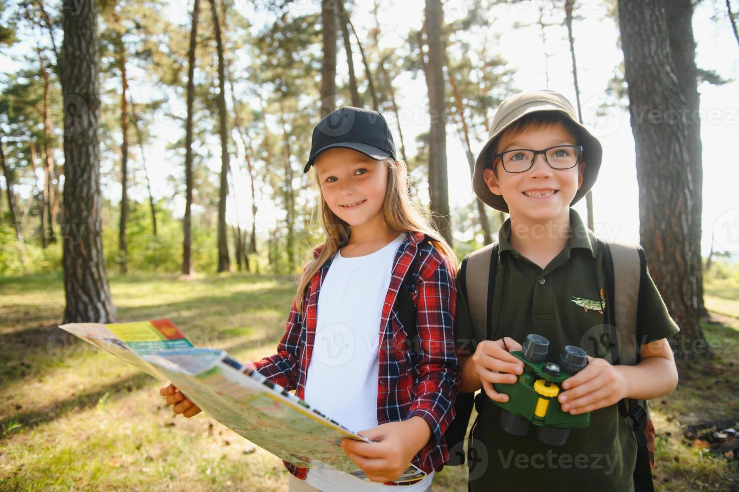 Happy excited school children with backpacks in casual clothes enjoying walk in forest on sunny autumn day, two active kids boy and girl running and playing together during camping trip in nature. photo