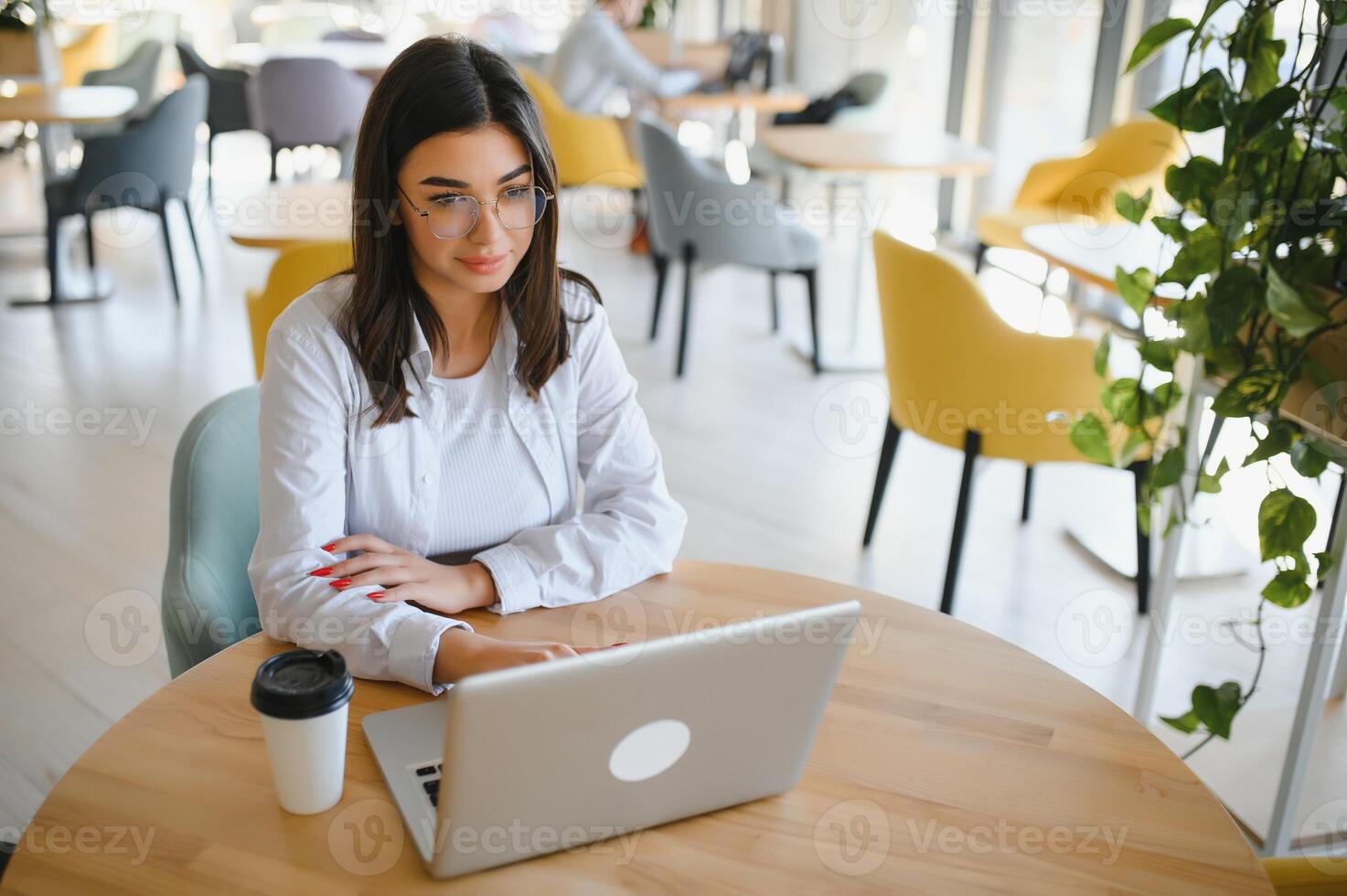 Joyful girl student studying online at cafe, using laptop and earphones, empty space photo