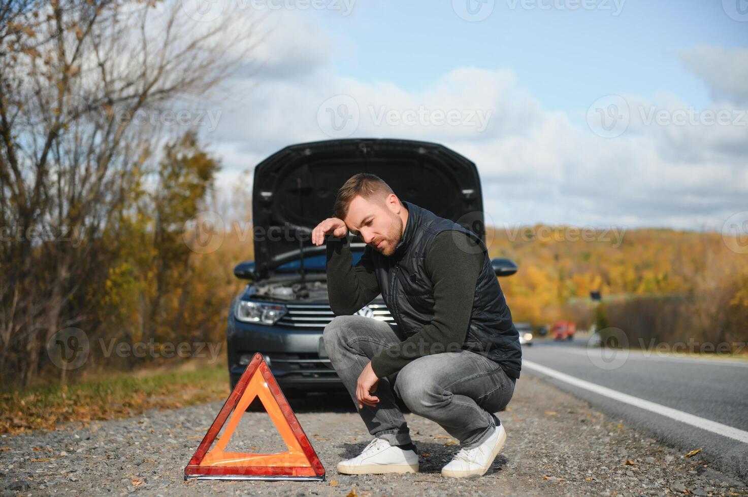 Handsome young man with his car broken down by the roadside photo