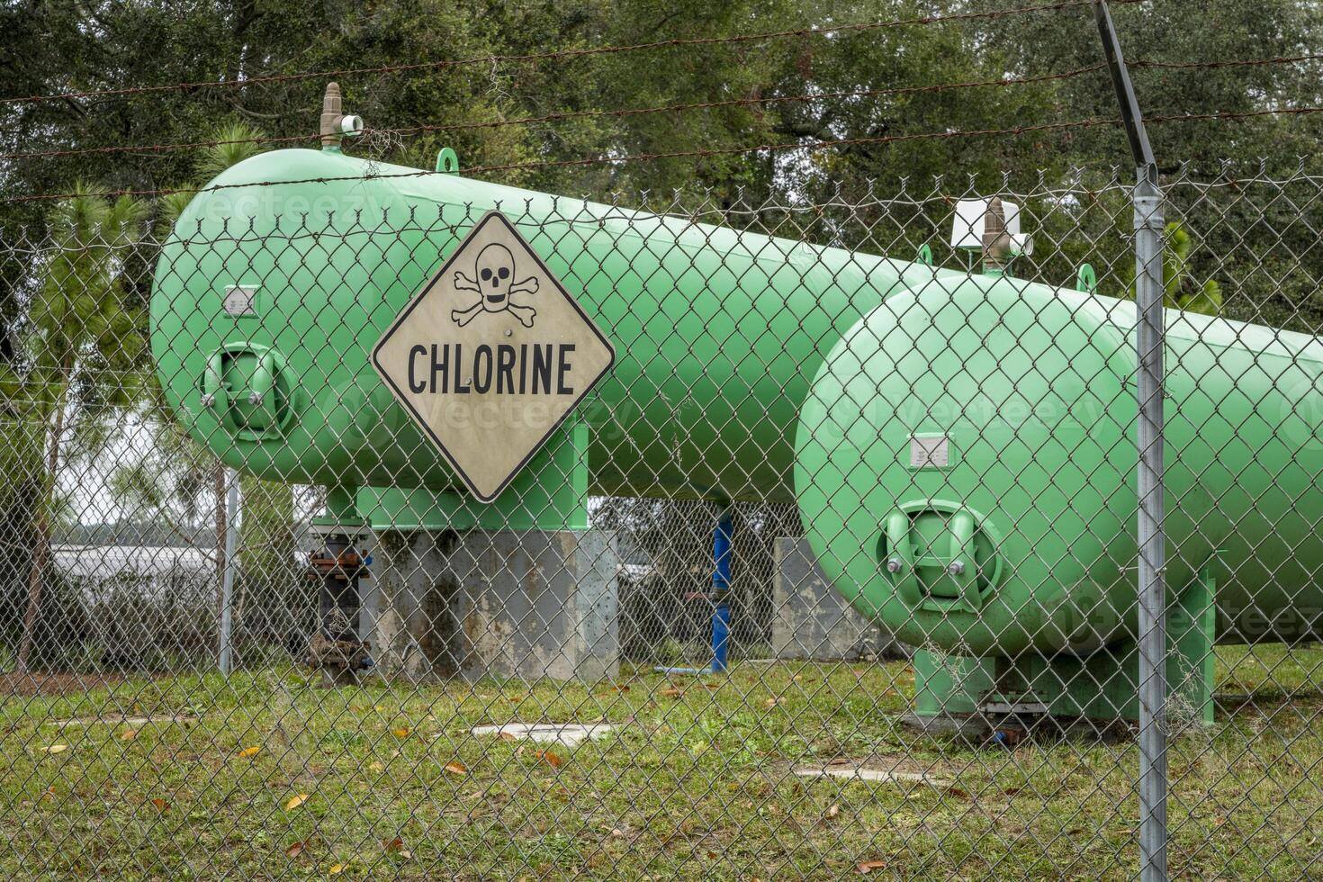 industrial chlorine gas tanks behind a fence with a warning sign photo