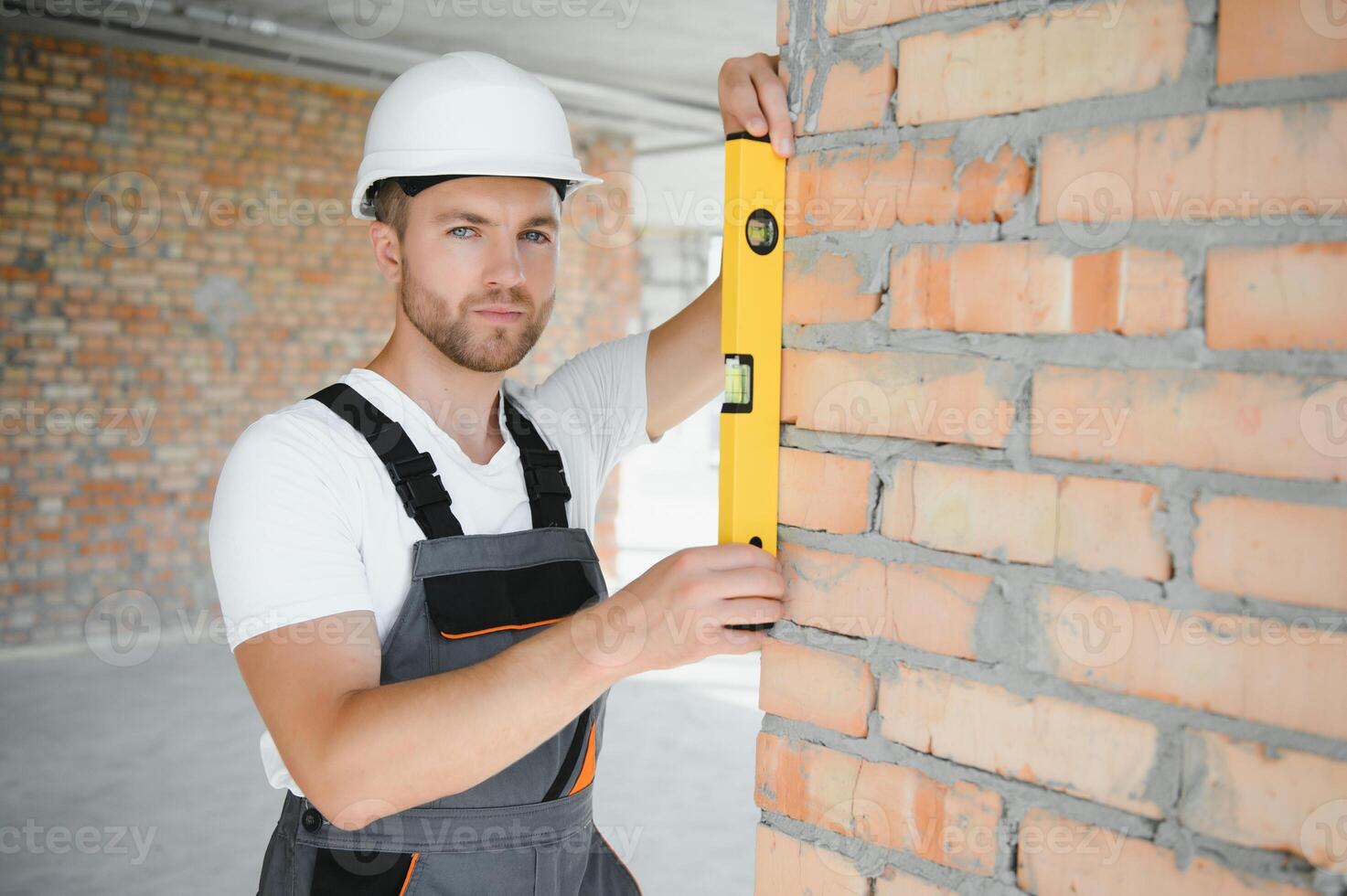 Portrait of handsome male builder in overalls and hard hat photo