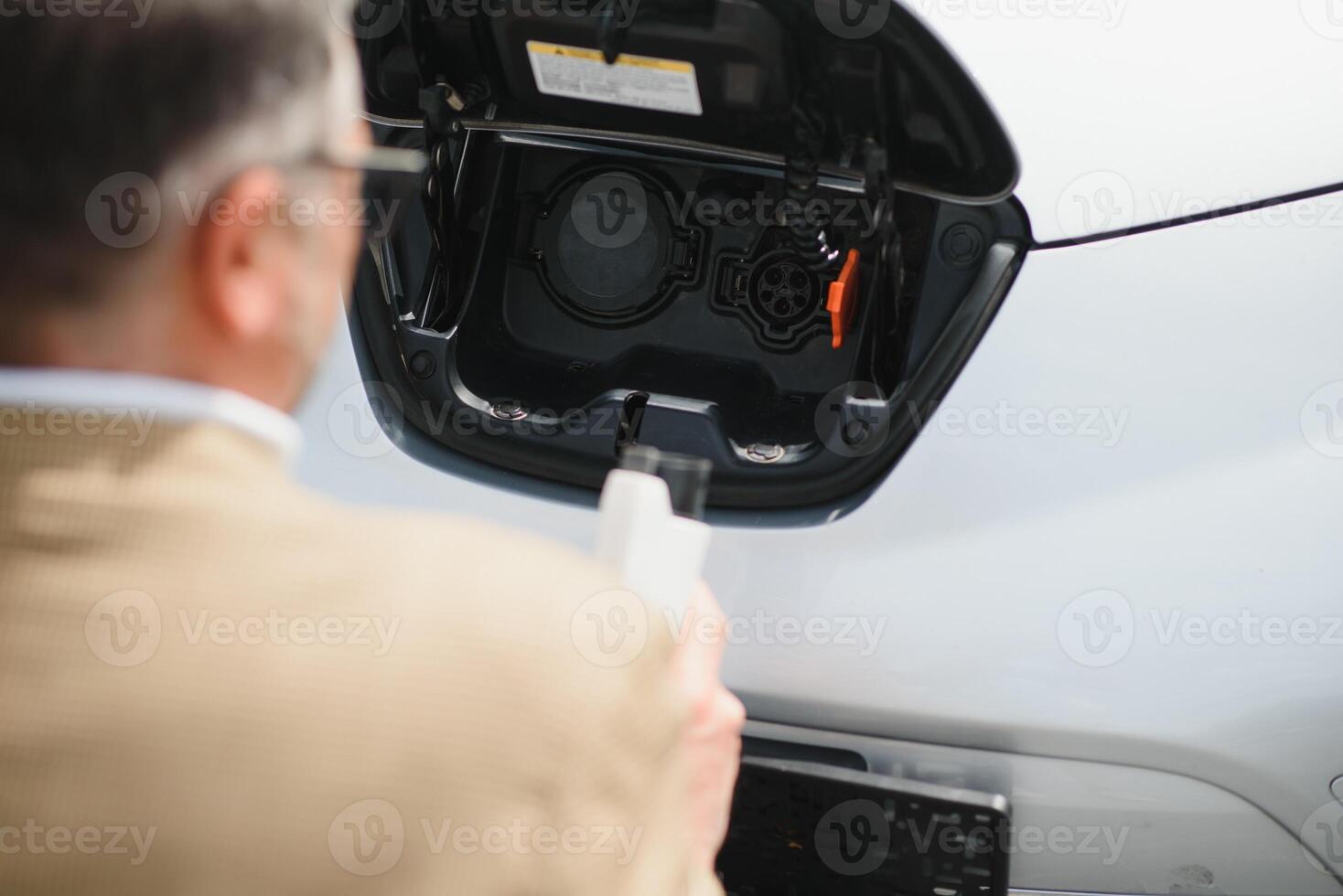 a businessman charges an electric car photo