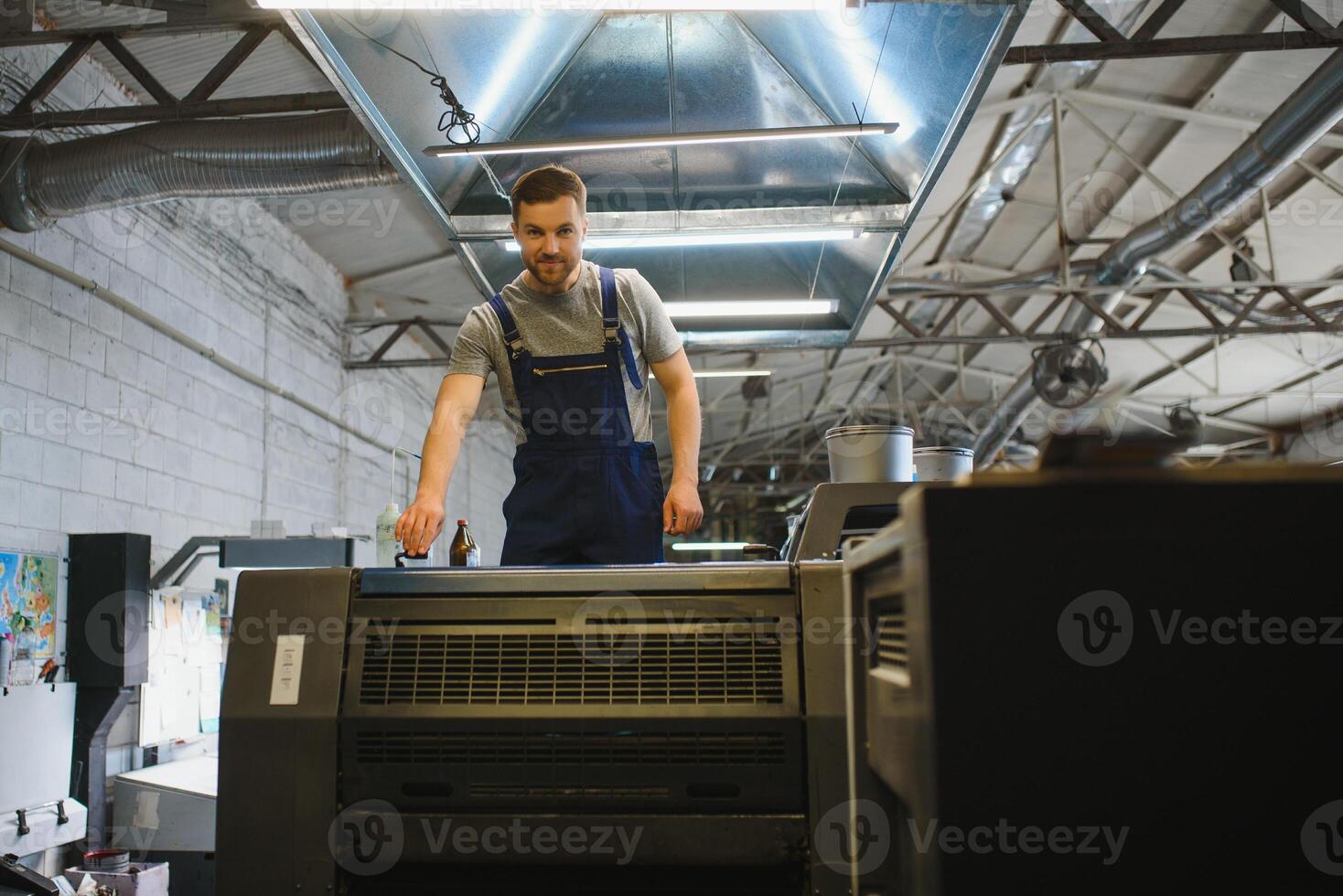 Man working in printing house with paper and paints photo