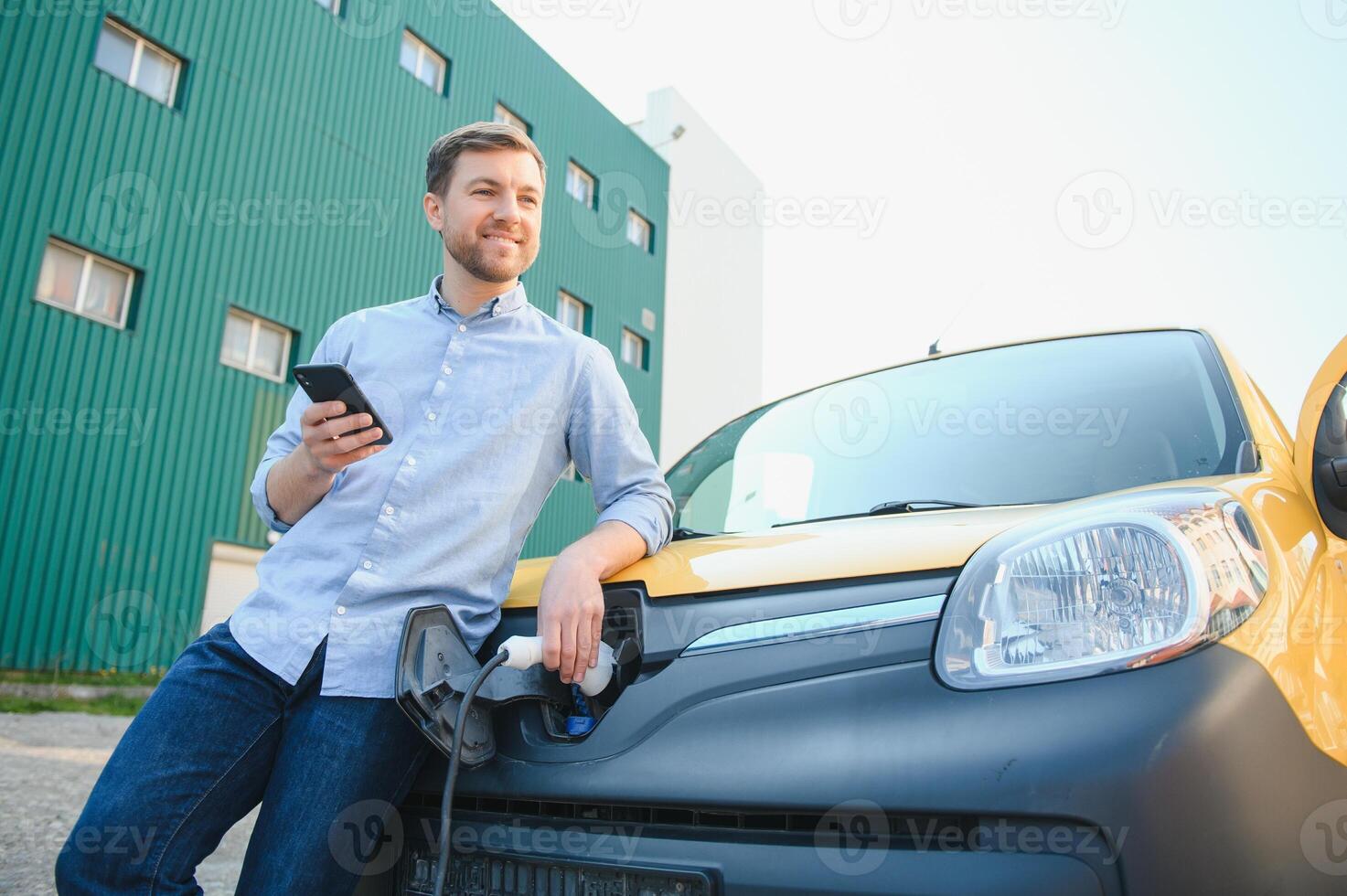 Smiling man unplugging the charger from the car photo