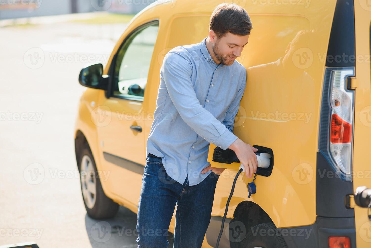 Smiling man unplugging the charger from the car photo