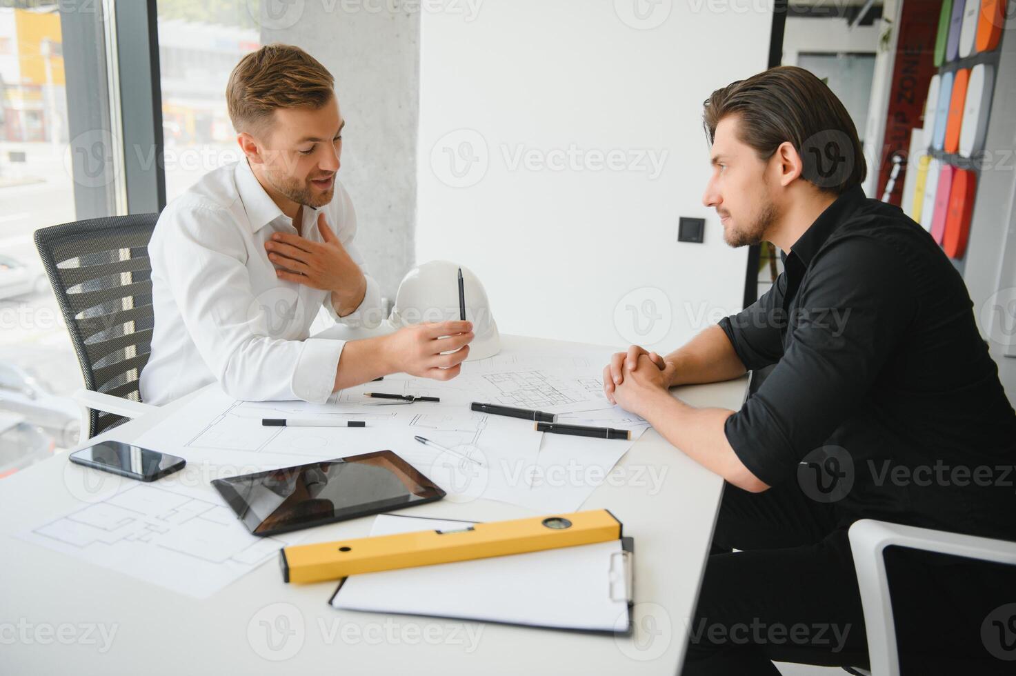 two people sit in front of construction plan and talk about the architecture photo