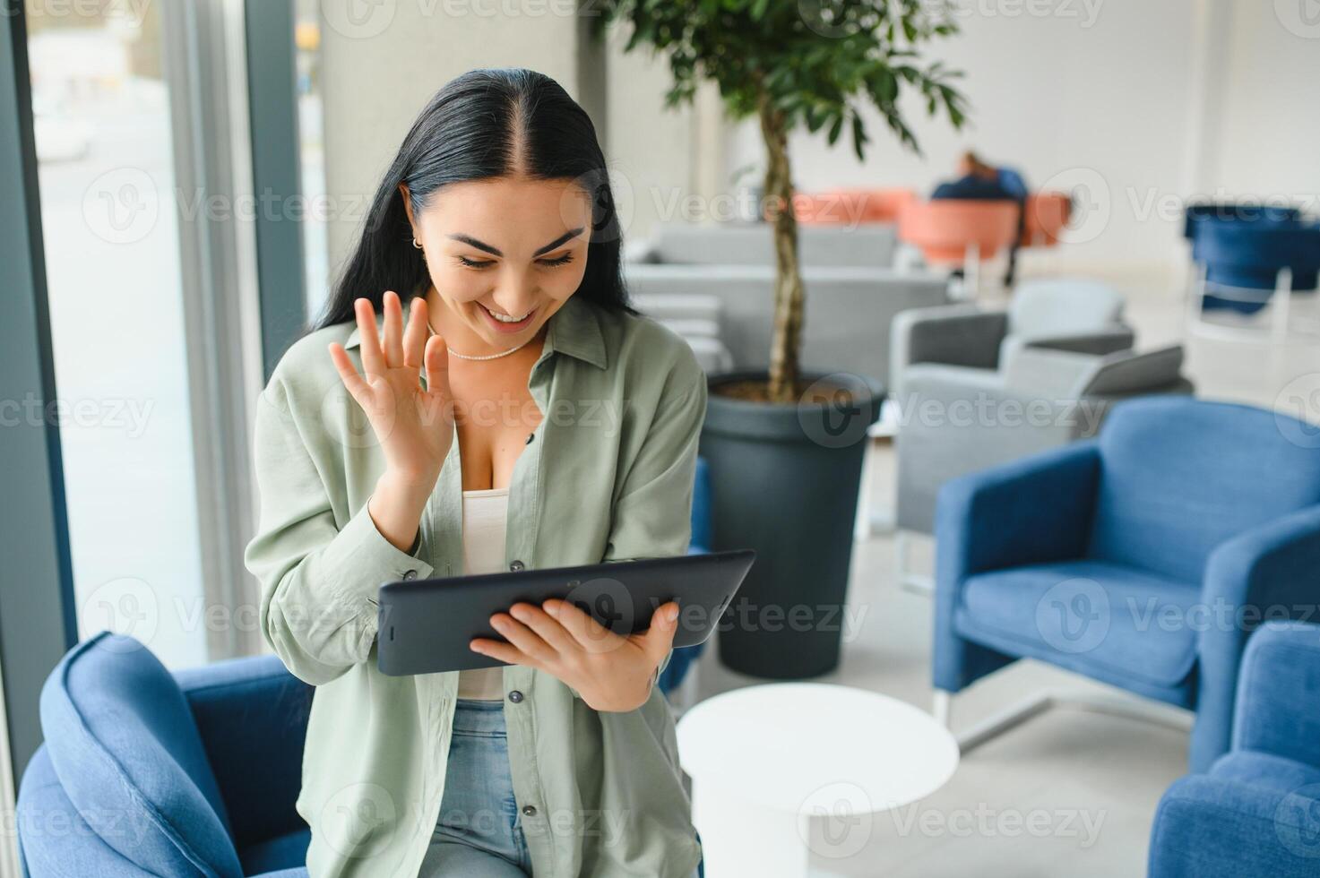 Traveler tourist woman with headphones working on laptop, spreading hands during video call while waiting in lobby hall at airport. Passenger traveling abroad on weekends getaway. Air flight concept photo