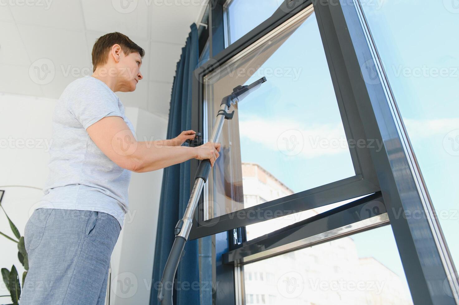 An attractive middle-aged woman is washing a window in a room photo