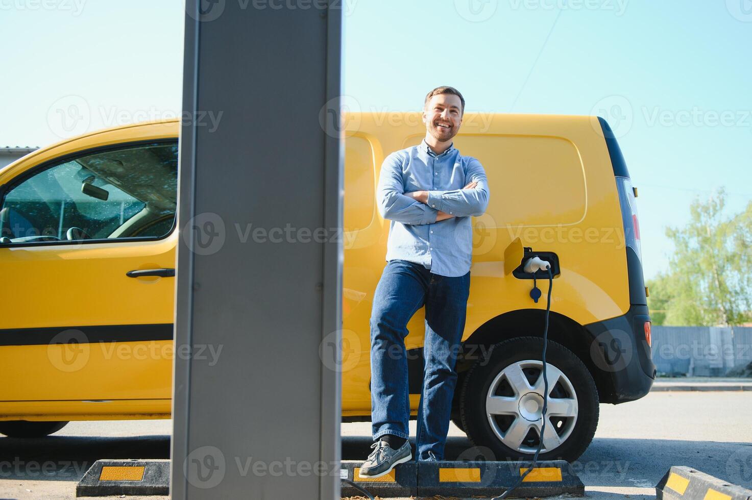 Hansome bearded guy near his new modern electric car at the charging station photo