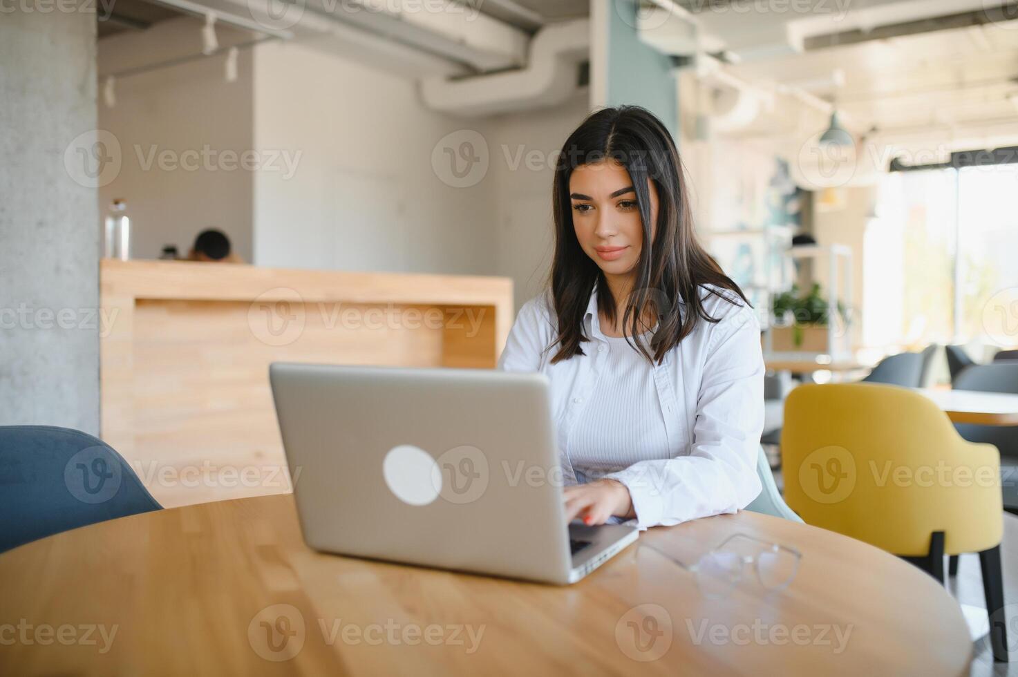 sonriente niña estudiante estudiar en línea con skype maestro, contento joven mujer aprender idioma escucha conferencia reloj seminario web escribir notas Mira a ordenador portátil sentar en cafetería, distante educación foto