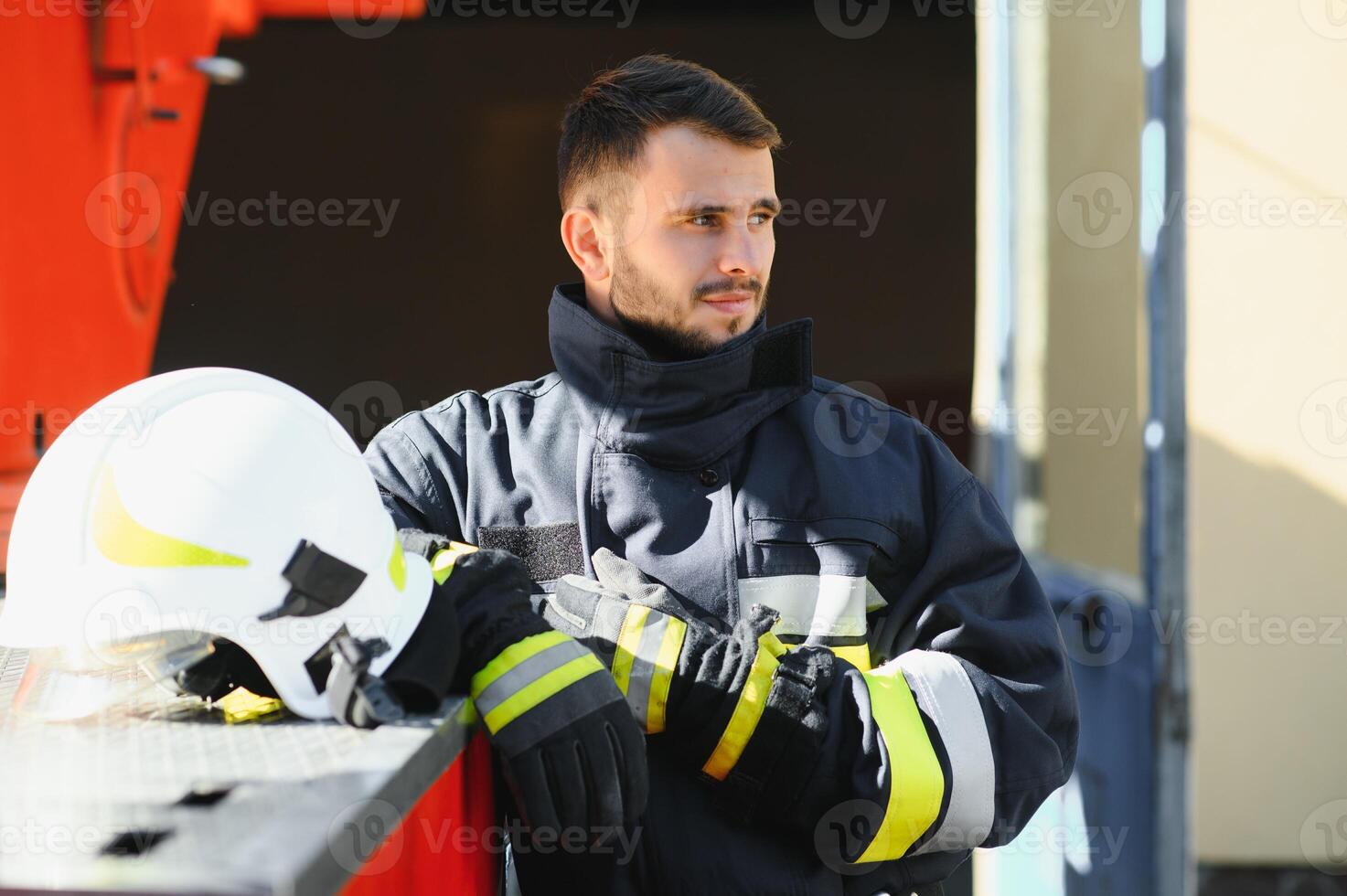 Firefighter portrait on duty. Photo fireman with gas mask and helmet near fire engine.