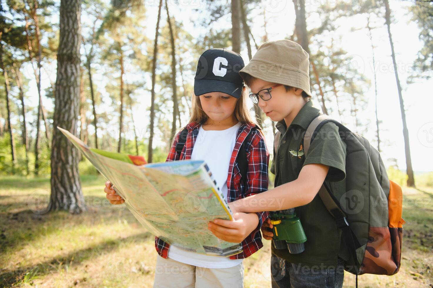 Happy excited school children with backpacks in casual clothes enjoying walk in forest on sunny autumn day, two active kids boy and girl running and playing together during camping trip in nature. photo